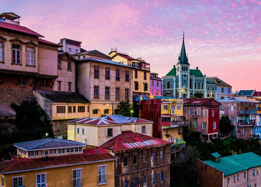 Passeio e tour em Valparaiso e Viña del Mar com conjunto de casas coloridas e antiga igreja ao fundo